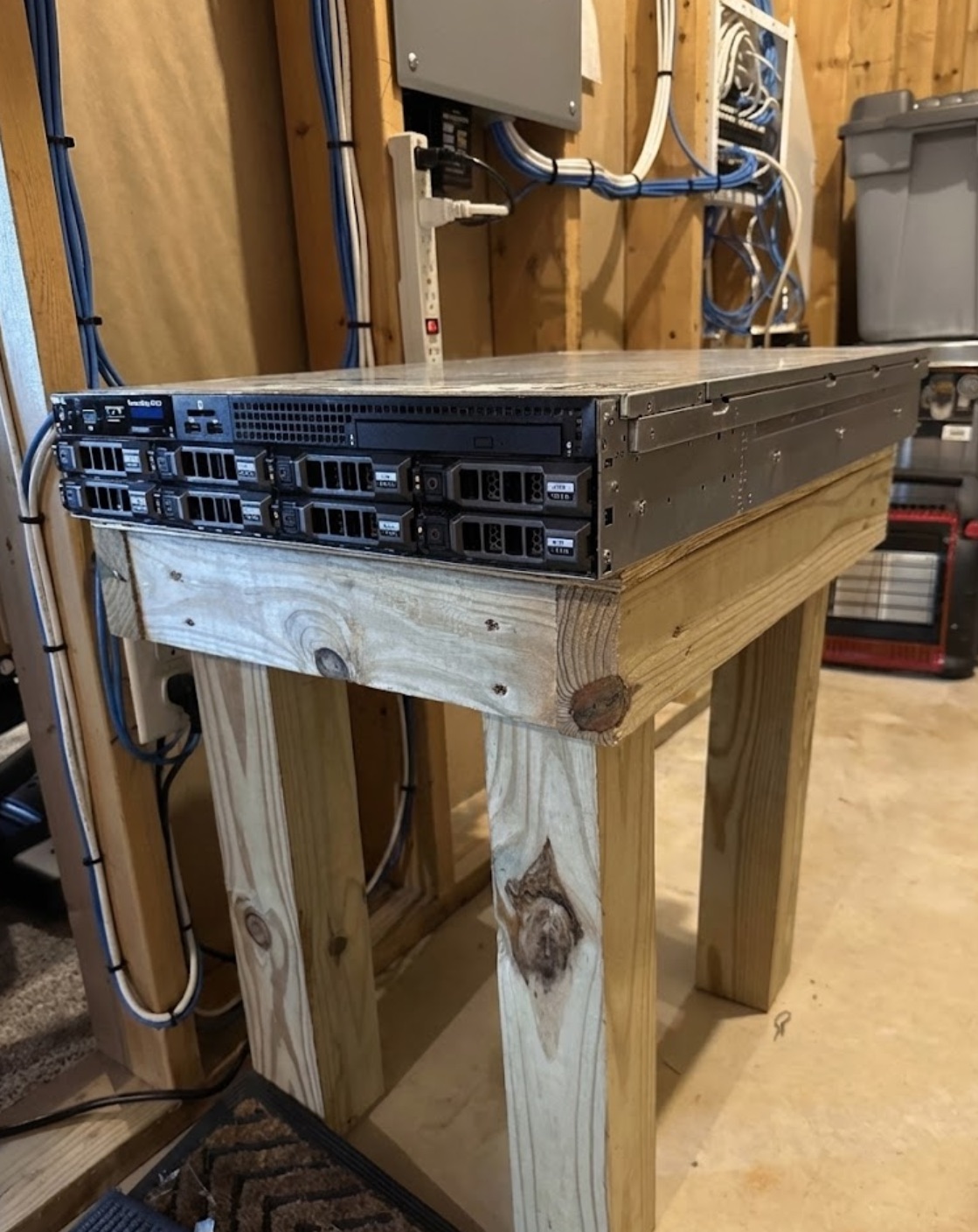 Dell rackmount server on a custom-built wooden stand with wall-mounted networking panel and cabling